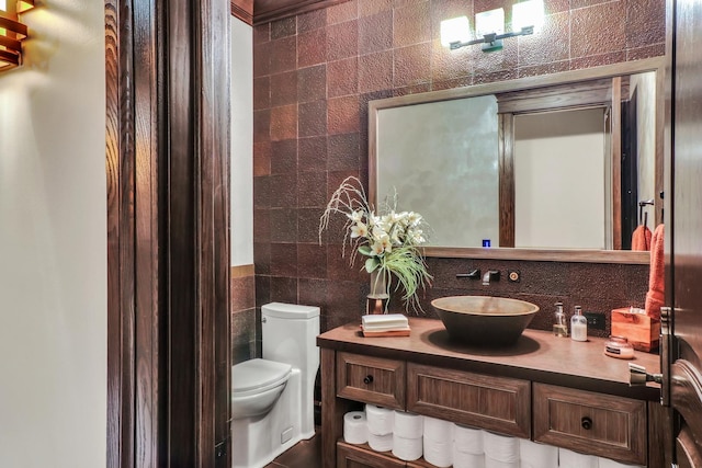 bathroom featuring vanity, tile walls, toilet, and tasteful backsplash