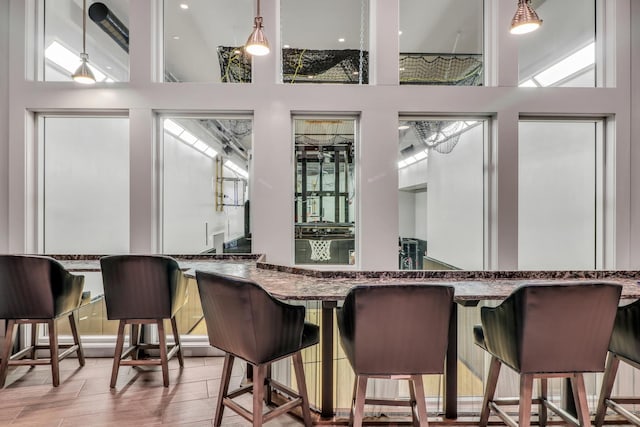 bar with pendant lighting, wet bar, a towering ceiling, and wood finished floors