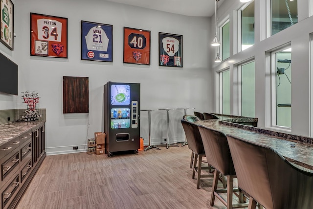 bar with decorative light fixtures, baseboards, and light wood-type flooring