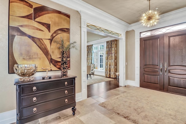 entryway featuring a notable chandelier, baseboards, and ornamental molding