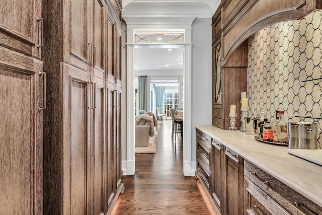 bar with dark wood finished floors and crown molding