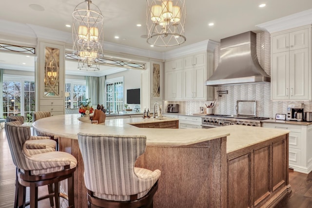 kitchen featuring a spacious island, tasteful backsplash, wall chimney range hood, dark wood finished floors, and gas stove