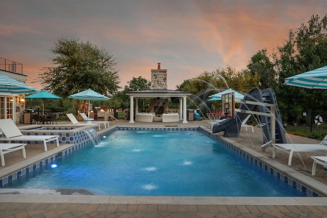 pool at dusk with a patio, a community pool, and an outdoor hangout area