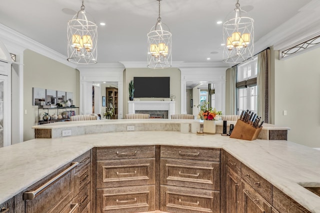 kitchen featuring ornamental molding, light stone countertops, open floor plan, and a chandelier