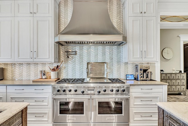 kitchen featuring white cabinetry, custom range hood, and double oven range