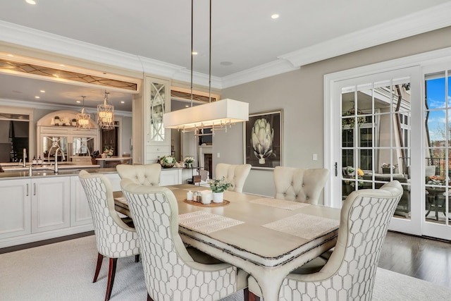 dining area with an inviting chandelier, recessed lighting, wood finished floors, and ornamental molding