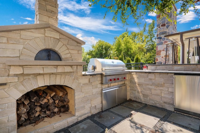 view of patio / terrace featuring area for grilling, exterior kitchen, and an outdoor stone fireplace