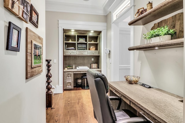 home office featuring light wood-style flooring, built in desk, and crown molding