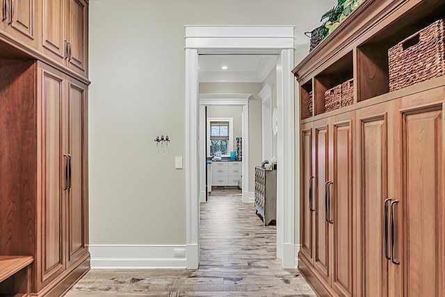 mudroom with baseboards, crown molding, and light wood finished floors