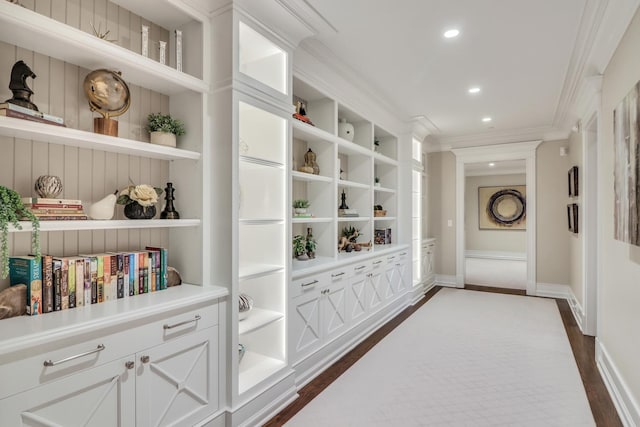 interior space featuring built in shelves, baseboards, ornamental molding, recessed lighting, and dark wood-style flooring