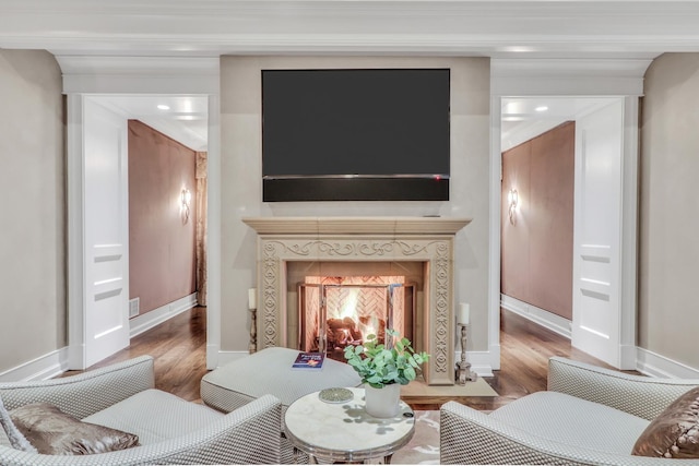 living room with a warm lit fireplace, baseboards, and wood finished floors