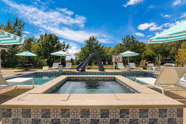 view of swimming pool featuring a patio, fence, a water slide, a fenced in pool, and an in ground hot tub