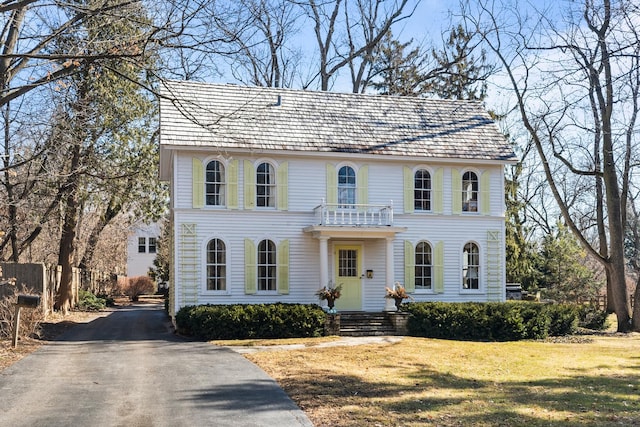 view of front facade featuring a front yard, a balcony, and driveway