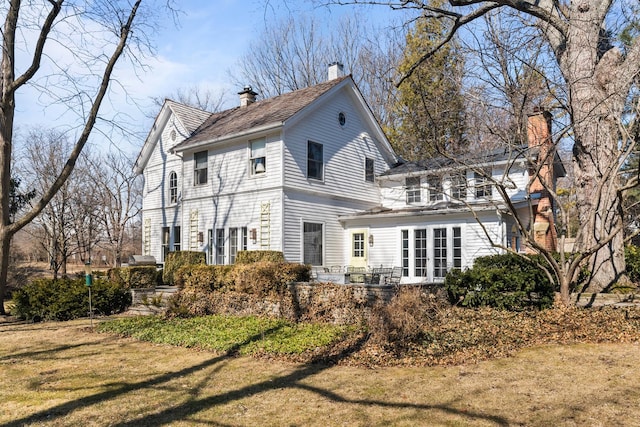 rear view of house featuring a yard and a chimney