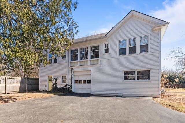 back of property featuring aphalt driveway, a garage, and fence