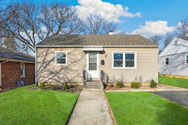 bungalow-style home with entry steps, a chimney, a front lawn, and a shingled roof