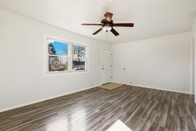 empty room with wood finished floors, a ceiling fan, and baseboards