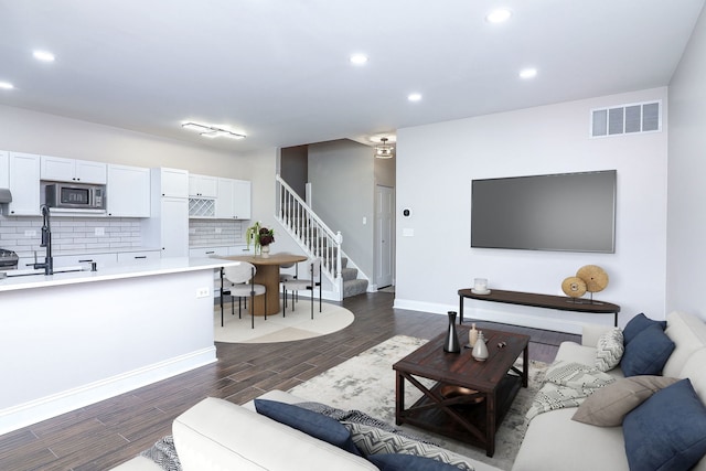 living room with visible vents, recessed lighting, stairs, and dark wood-style flooring