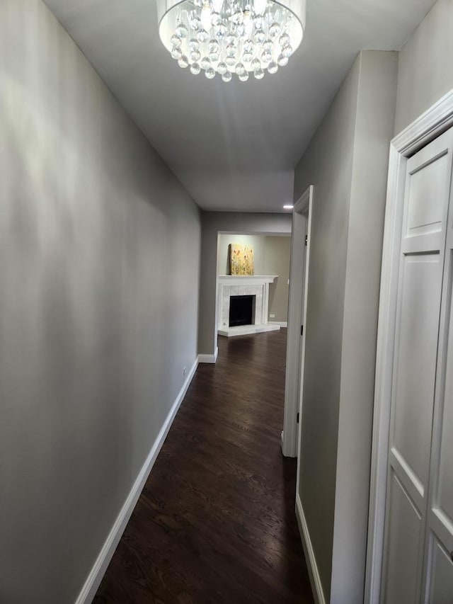 hall with a chandelier, baseboards, and dark wood-style floors