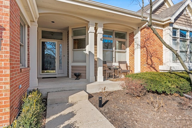 doorway to property with brick siding and covered porch