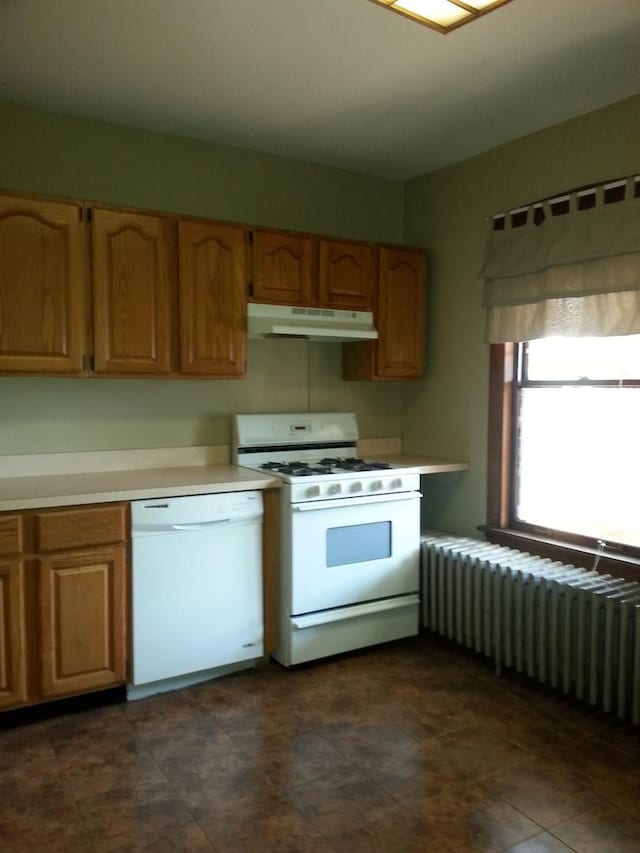 kitchen featuring under cabinet range hood, radiator heating unit, white appliances, brown cabinetry, and light countertops