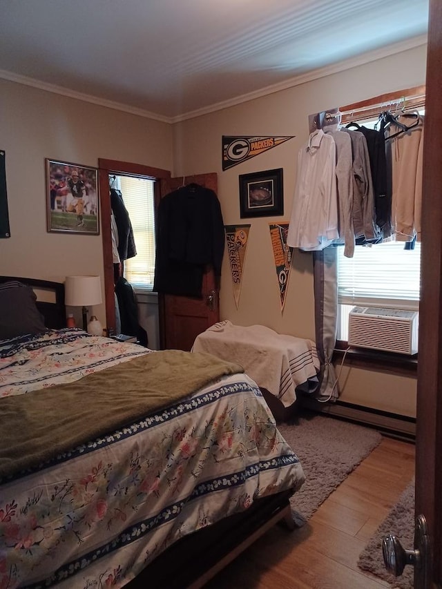 bedroom with cooling unit, crown molding, and wood finished floors