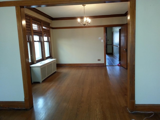 unfurnished dining area with radiator, wood finished floors, baseboards, crown molding, and a notable chandelier