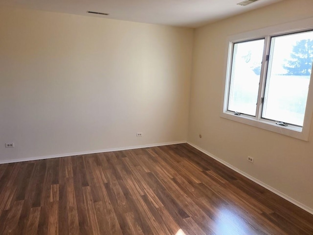 unfurnished room featuring visible vents, baseboards, and dark wood-style flooring