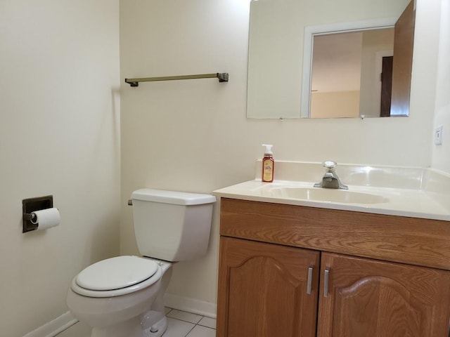 half bathroom featuring baseboards, toilet, vanity, and tile patterned flooring