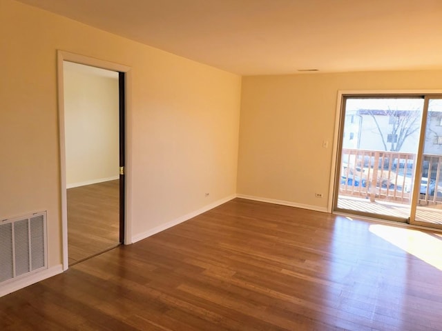 empty room featuring visible vents, baseboards, and wood finished floors