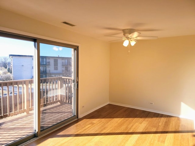 spare room featuring visible vents, ceiling fan, baseboards, and wood finished floors