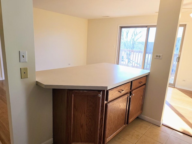 kitchen featuring light countertops, light tile patterned floors, a peninsula, and baseboards