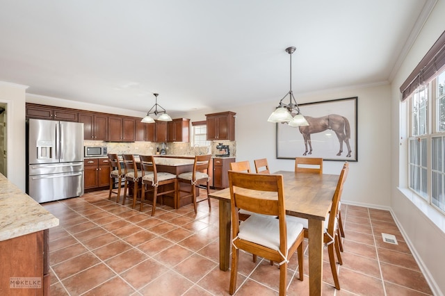 dining space featuring light tile patterned floors, visible vents, baseboards, and ornamental molding