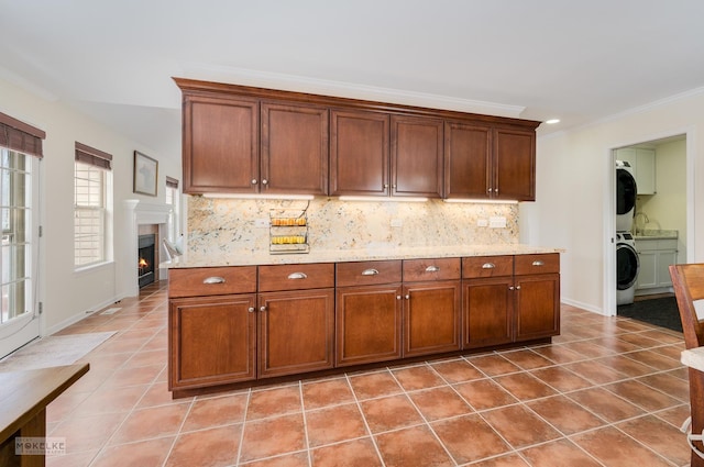 kitchen with backsplash, baseboards, a lit fireplace, ornamental molding, and light tile patterned flooring