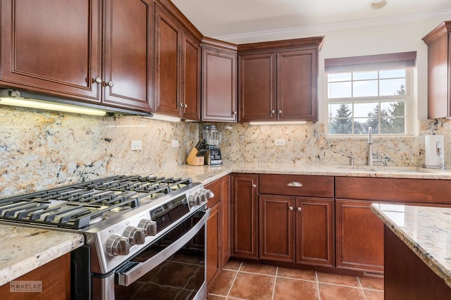 kitchen featuring stainless steel range with gas stovetop, light stone countertops, crown molding, and a sink