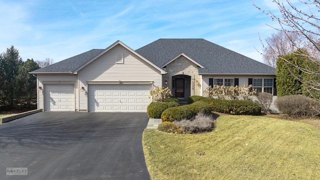 ranch-style house featuring driveway, a front yard, a garage, and roof with shingles