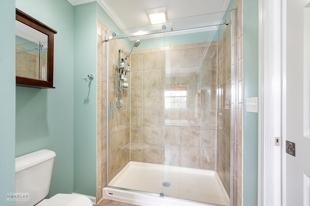 bathroom with a shower stall, toilet, and crown molding