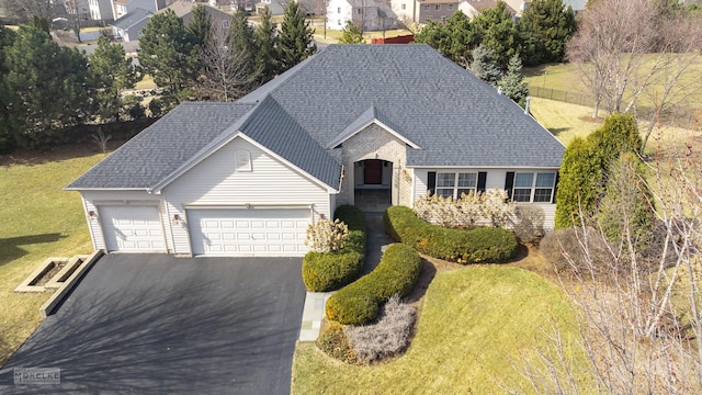 view of front of property featuring driveway, a shingled roof, a garage, and a front yard