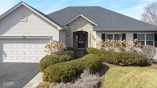 view of front facade with aphalt driveway, a garage, and a shingled roof