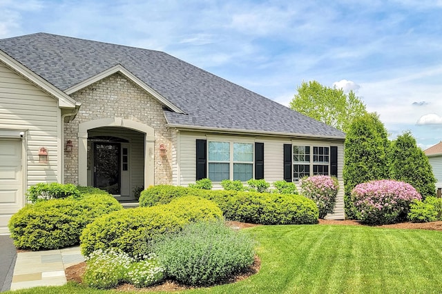 view of front of home with stone siding, roof with shingles, and a front lawn