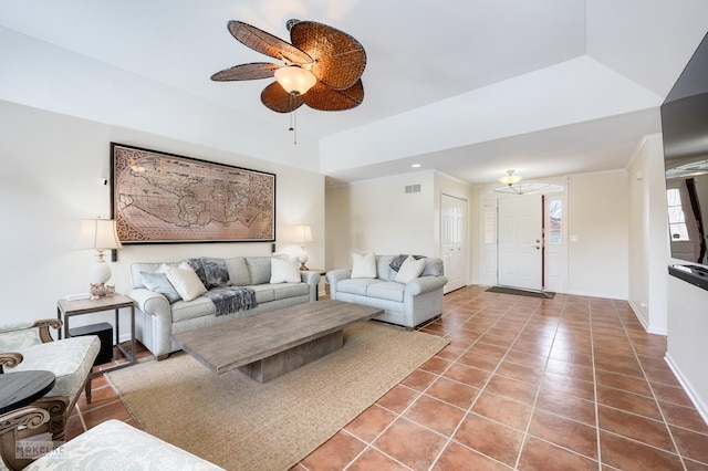 living area with baseboards, visible vents, ceiling fan, tile patterned flooring, and a raised ceiling