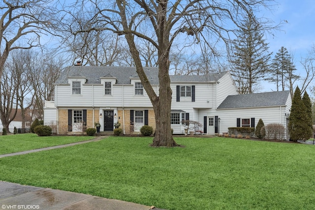 view of front of property with a shingled roof, a front yard, and a chimney