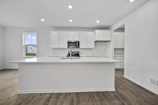 kitchen with light countertops, white cabinets, an island with sink, and appliances with stainless steel finishes