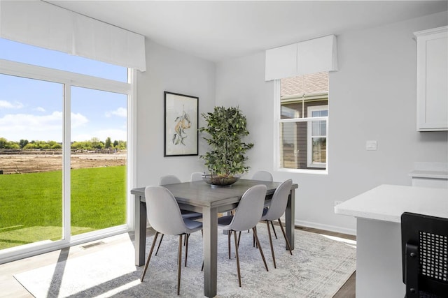 dining area featuring visible vents, wood finished floors, and baseboards