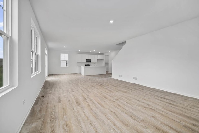 unfurnished living room featuring recessed lighting, light wood-style flooring, visible vents, and baseboards