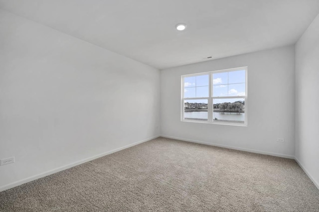 spare room featuring light colored carpet and baseboards