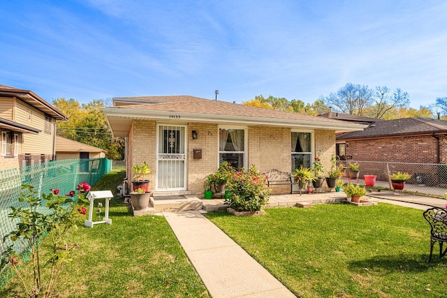 view of front of property featuring brick siding, a shingled roof, a front yard, and fence