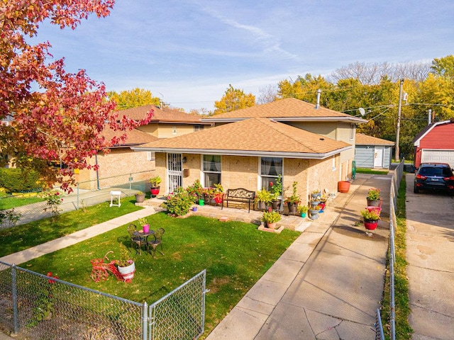 view of front of house featuring a shingled roof, a detached garage, fence private yard, a front yard, and an outdoor structure