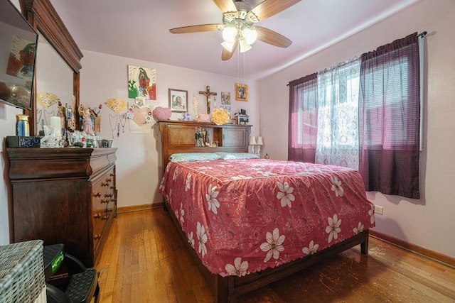 bedroom with hardwood / wood-style flooring, a ceiling fan, and baseboards