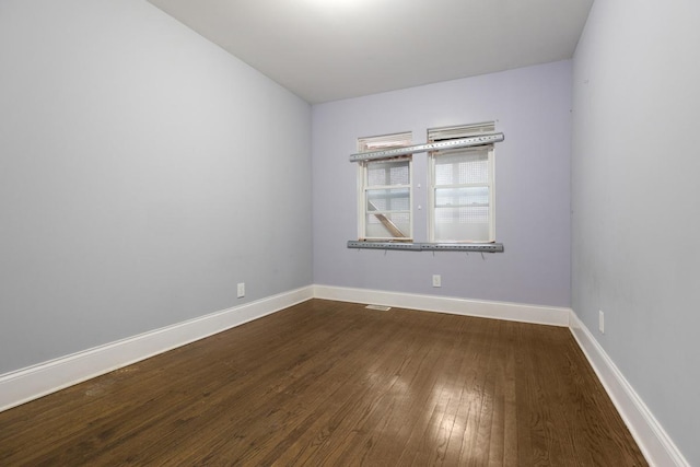 unfurnished room featuring dark wood-style floors and baseboards